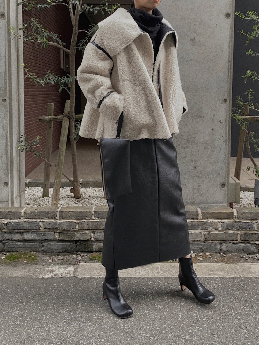 ブラック系のニット/セーター、ブラック系のブーツ、ブラック系のその他アウターを着用したレディースの秋コーディネートの2枚目の写真