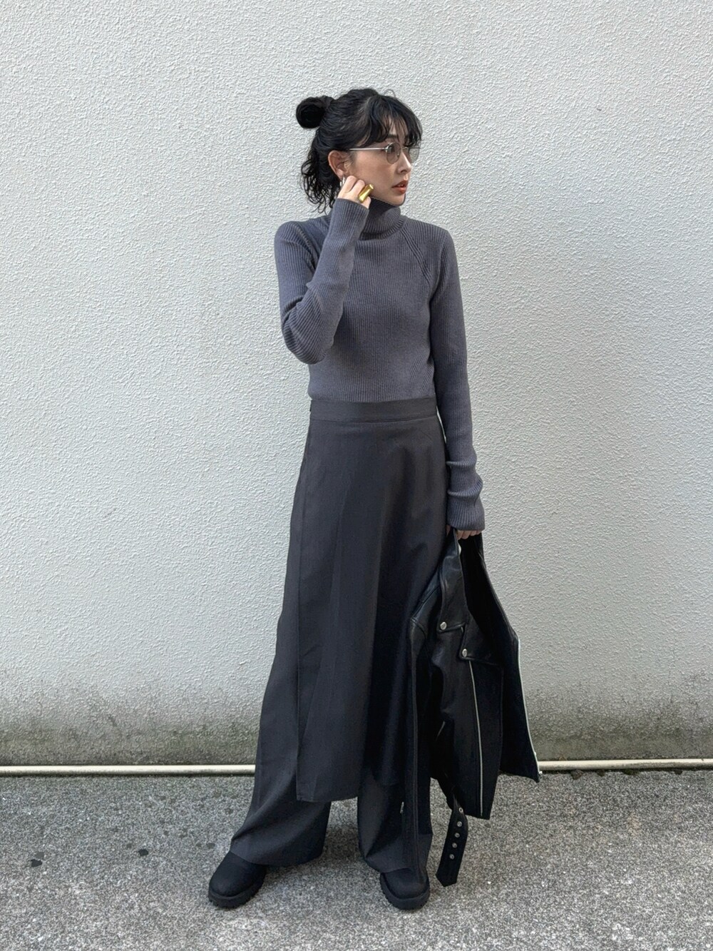 グレー系のニット/セーター、グレー系のスラックス、ブラック系のライダースジャケットを着用したレディースの秋コーディネートの3枚目の写真