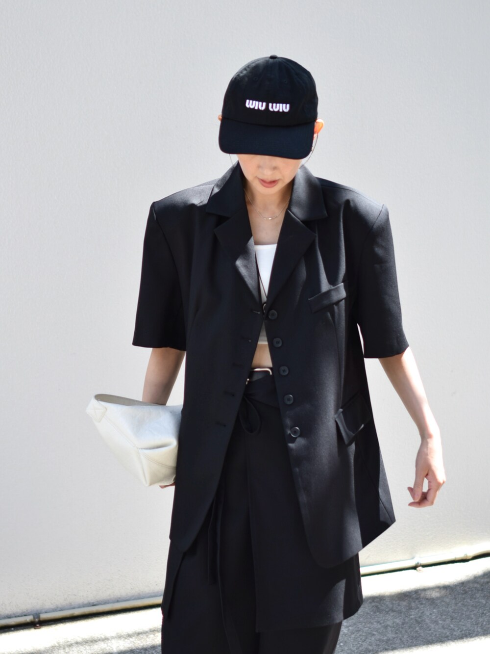 ブラック系のテーラードジャケット、ブラック系のスラックス、ホワイト系のショルダーバッグを着用したレディースの春コーディネートの3枚目の写真