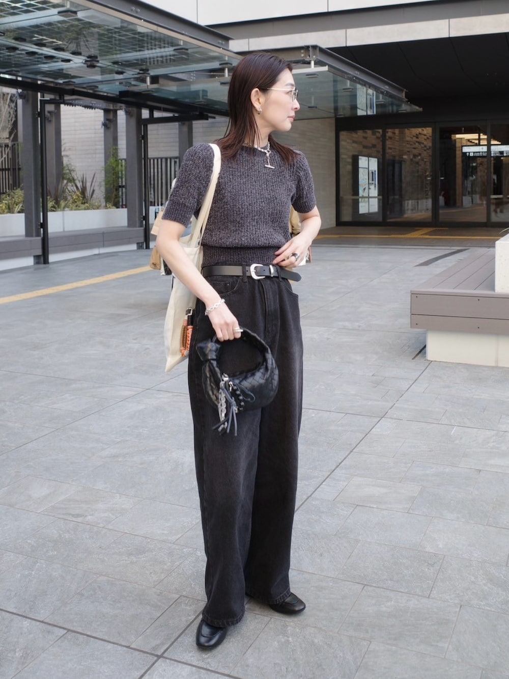 ブラック系のローファー、ブラック系のニット/セーター、ブラック系のデニムパンツを着用したレディースの春コーディネートの4枚目の写真