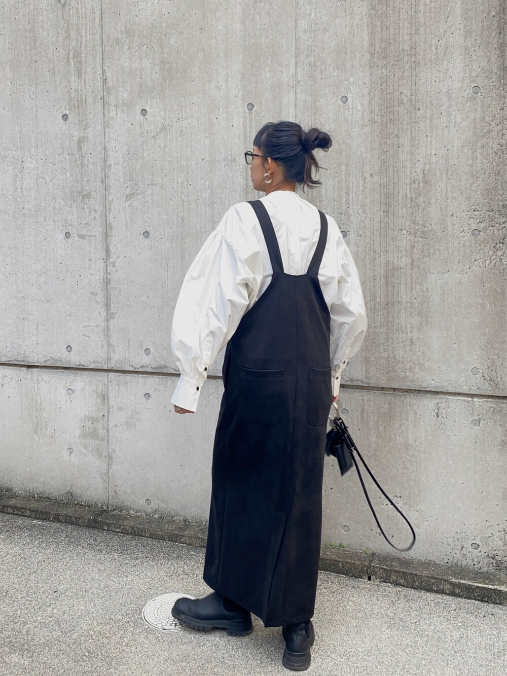 ブラック系のジャンパースカート、ブラック系のショルダーバッグ、ホワイト系のシャツ/ブラウスを着用したレディースの冬コーディネートの4枚目の写真