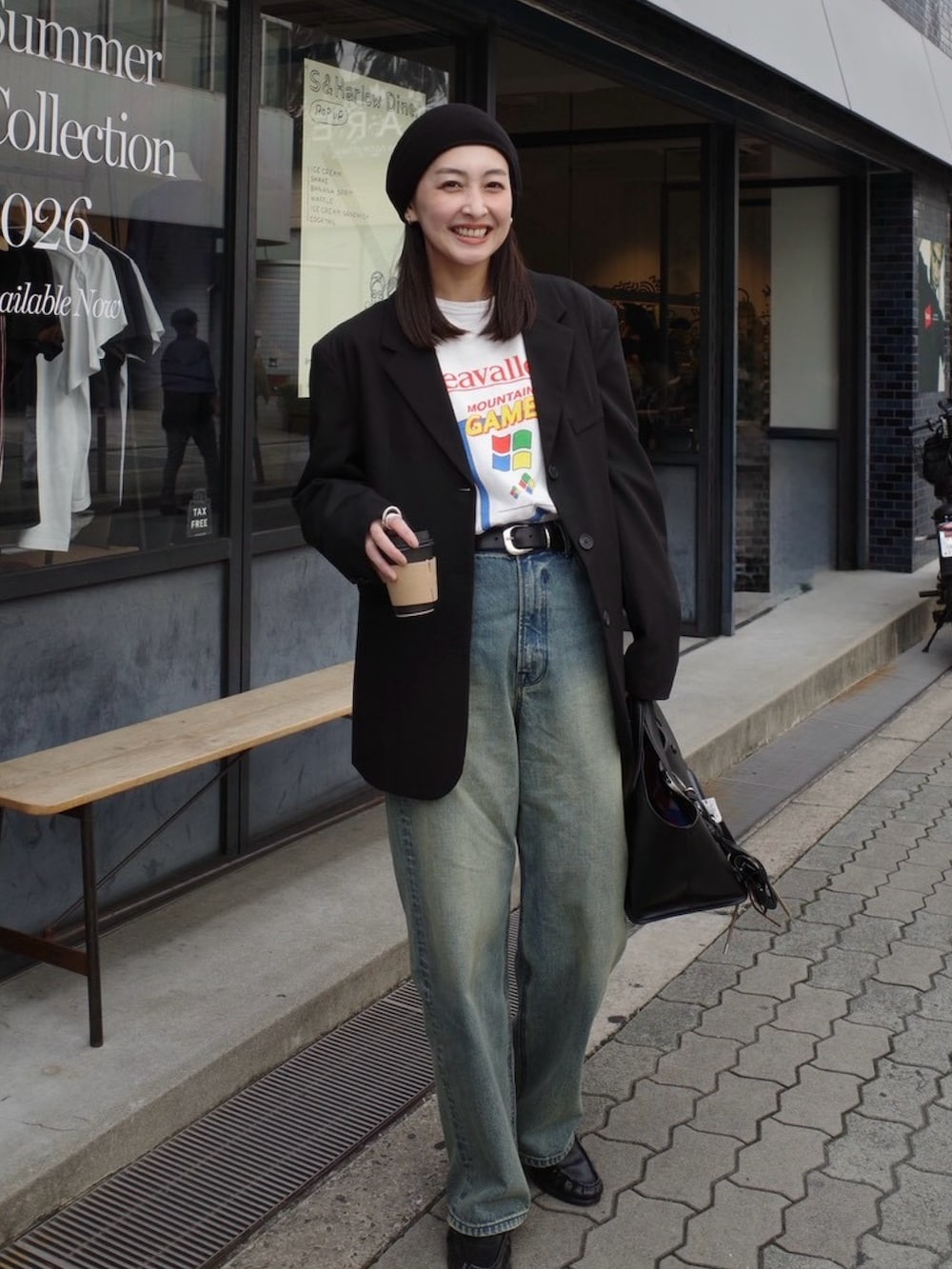 ブルー系のデニムパンツ、ブラック系のトートバッグ、ベージュ系のその他小物を着用したレディースの春コーディネートの5枚目の写真