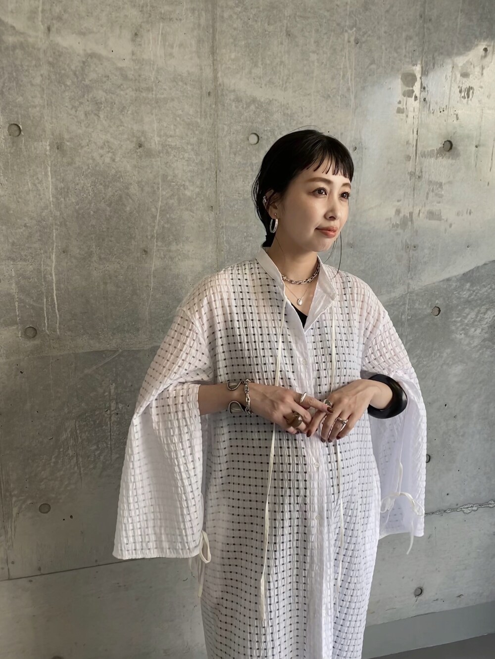 ホワイト系のワンピース、ベージュ系のハンドバッグ、ブラック系のサンダルを着用したレディースの夏コーディネートの2枚目の写真