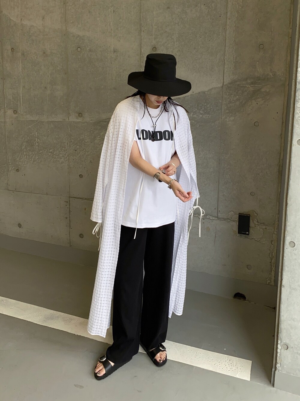 ホワイト系のワンピース、ホワイト系のTシャツ/カットソー、ブラック系のサンダルを着用したレディースの夏コーディネートの2枚目の写真