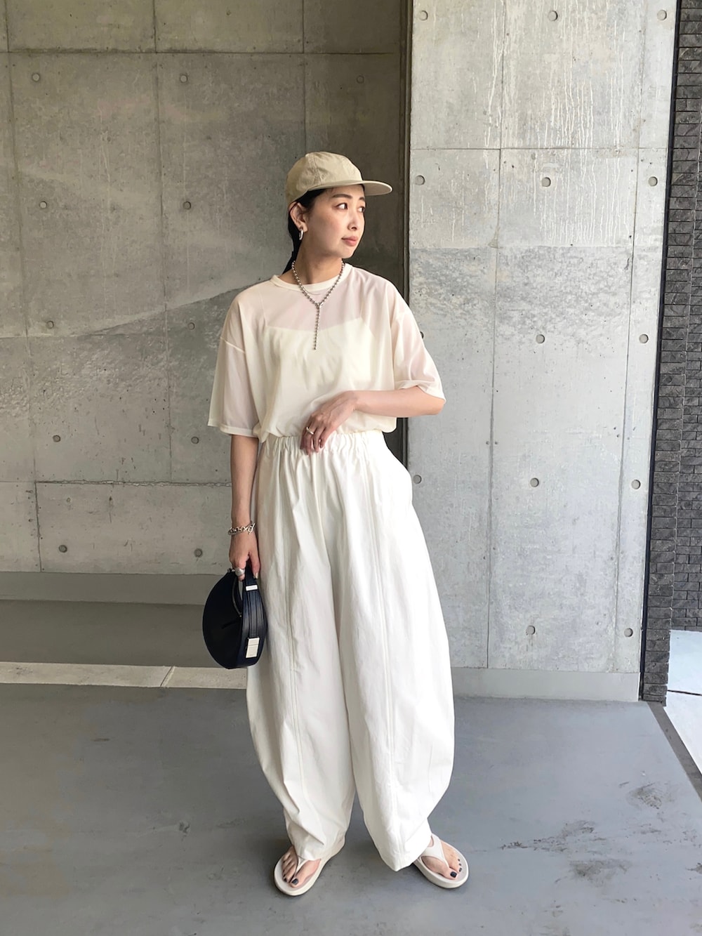 ホワイト系のTシャツ/カットソー、ホワイト系のチノパンツ、ホワイト系のサンダルを着用したレディースの夏コーディネートの3枚目の写真