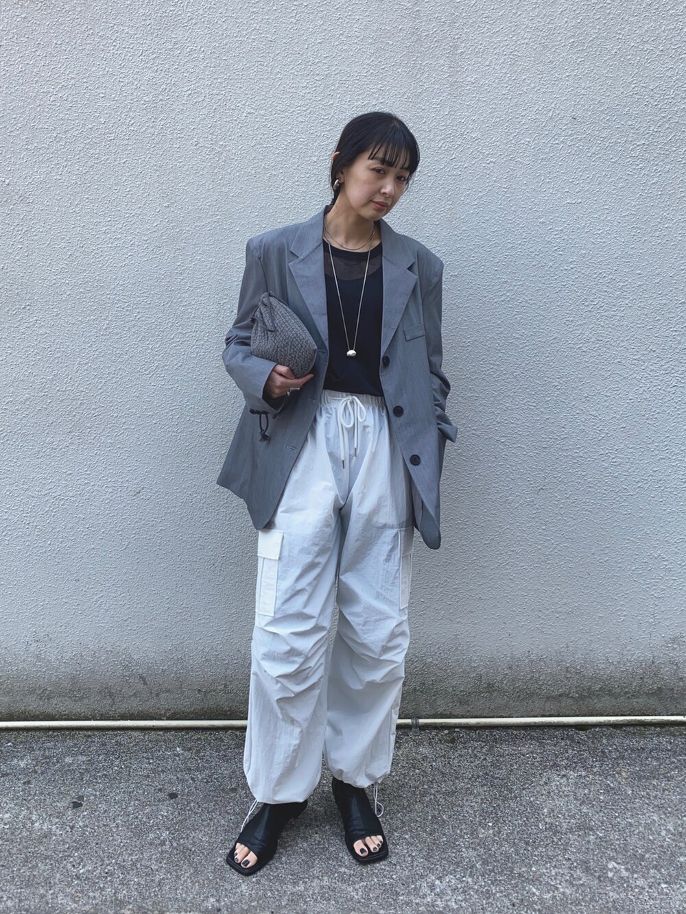 グレー系のテーラードジャケット、ホワイト系のカーゴパンツ、シルバー系のネックレスを着用したレディースの春コーディネートの5枚目の写真