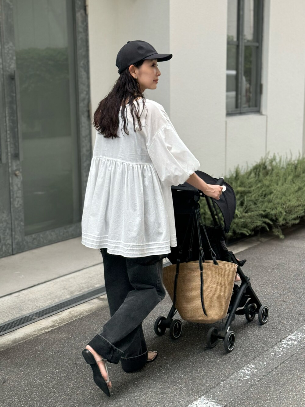 ホワイト系のチュニック、ブラック系のデニムパンツ、ベージュ系のトートバッグを着用したレディースの夏コーディネートの4枚目の写真