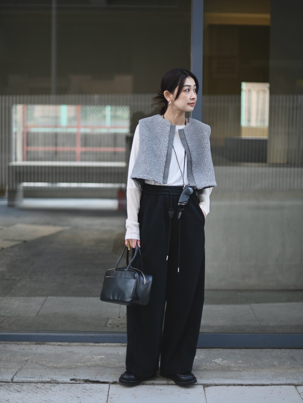 グレー系のベスト、ブラック系のスウェットパンツ、ブラック系のメガネを着用したレディースの冬コーディネートの4枚目の写真