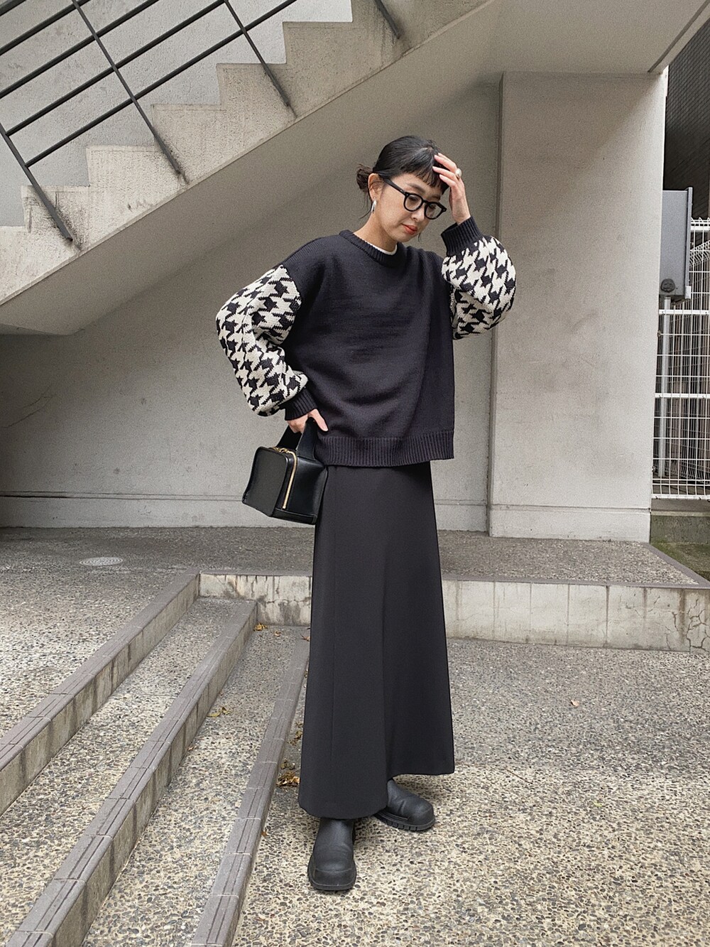 ブラック系のニット/セーター、ブラック系のダウンベスト、ブラック系のスカートを着用したレディースの冬コーディネートの2枚目の写真