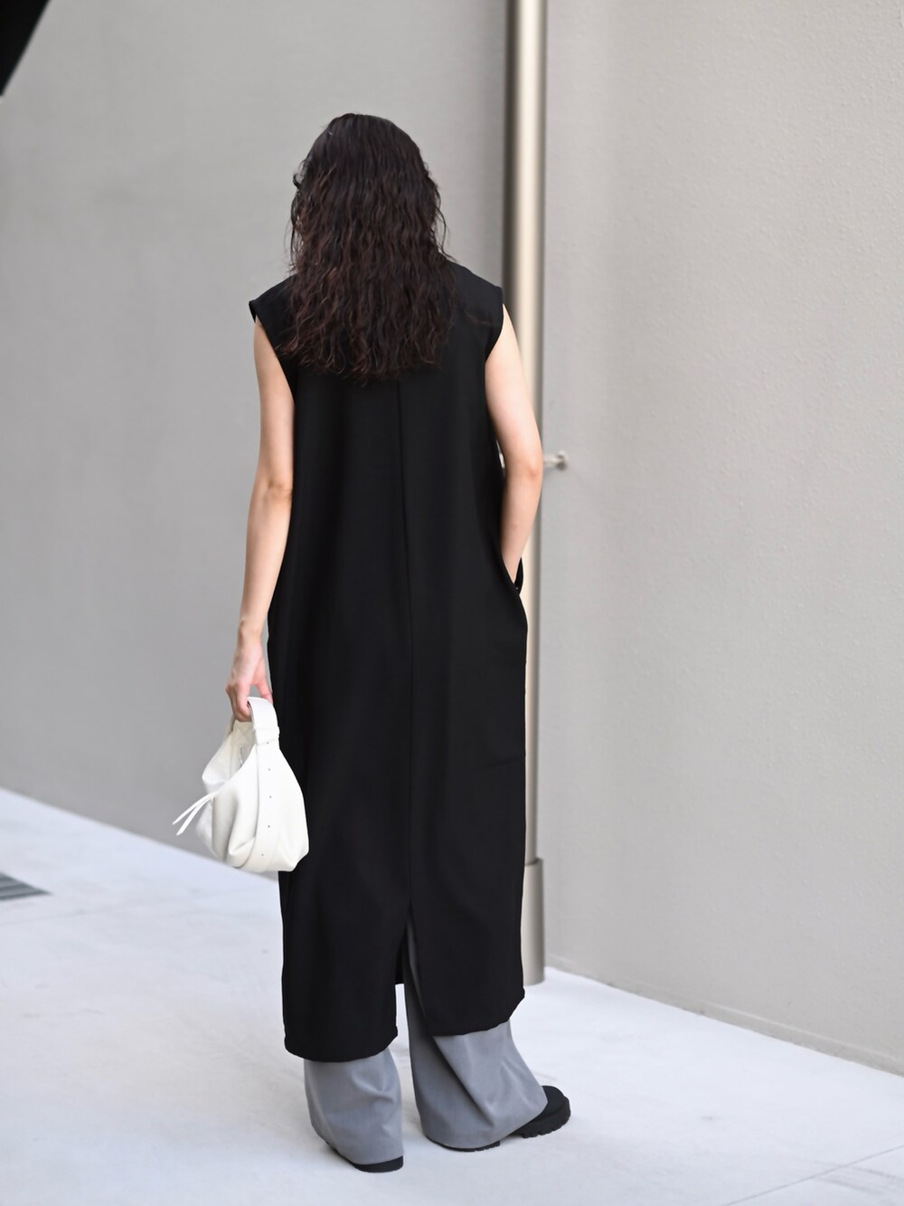 ブラック系のワンピース、ホワイト系のショルダーバッグ、グレー系のスラックスを着用したレディースの秋コーディネートの2枚目の写真