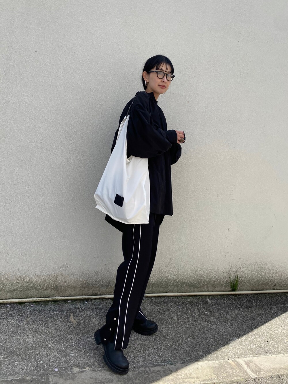 ブラック系のシャツ/ブラウス、ブラック系のその他パンツ、ホワイト系のエコバッグ/サブバッグを着用したレディースの春コーディネートの2枚目の写真