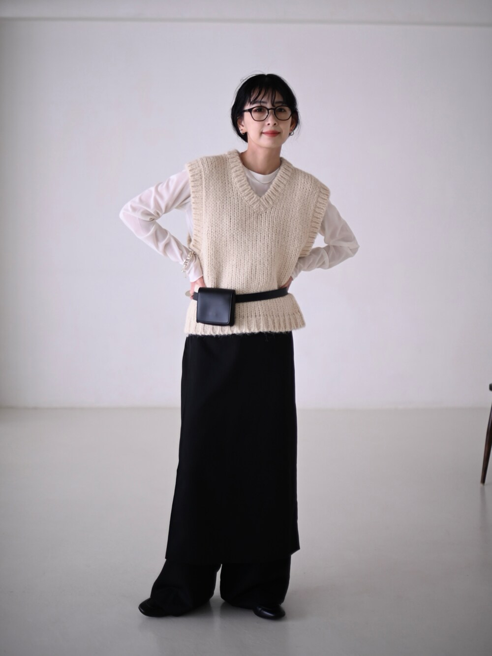 ホワイト系のベスト、ホワイト系のTシャツ/カットソー、ブラック系のスラックスを着用したレディースの冬コーディネートの2枚目の写真