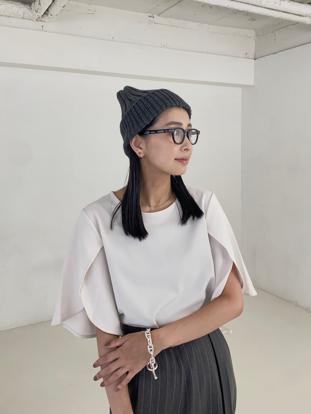 ホワイト系のTシャツ/カットソー、ブラック系のハンドバッグ、ブラック系のブーツを着用したレディースの秋コーディネートの2枚目の写真