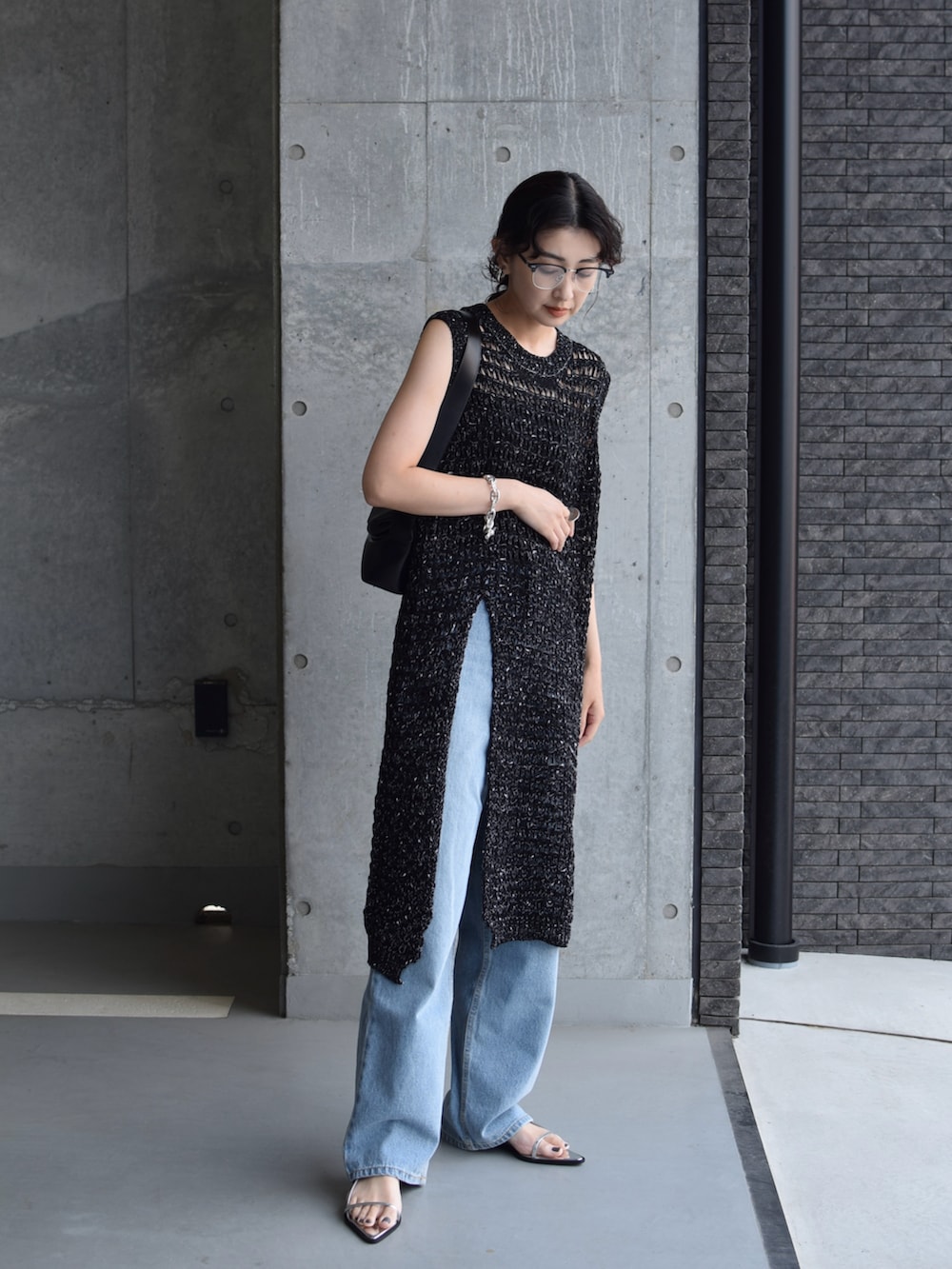 ブラック系のワンピース、ブルー系のデニムパンツ、シルバー系のサンダルを着用したレディースの夏コーディネートの4枚目の写真