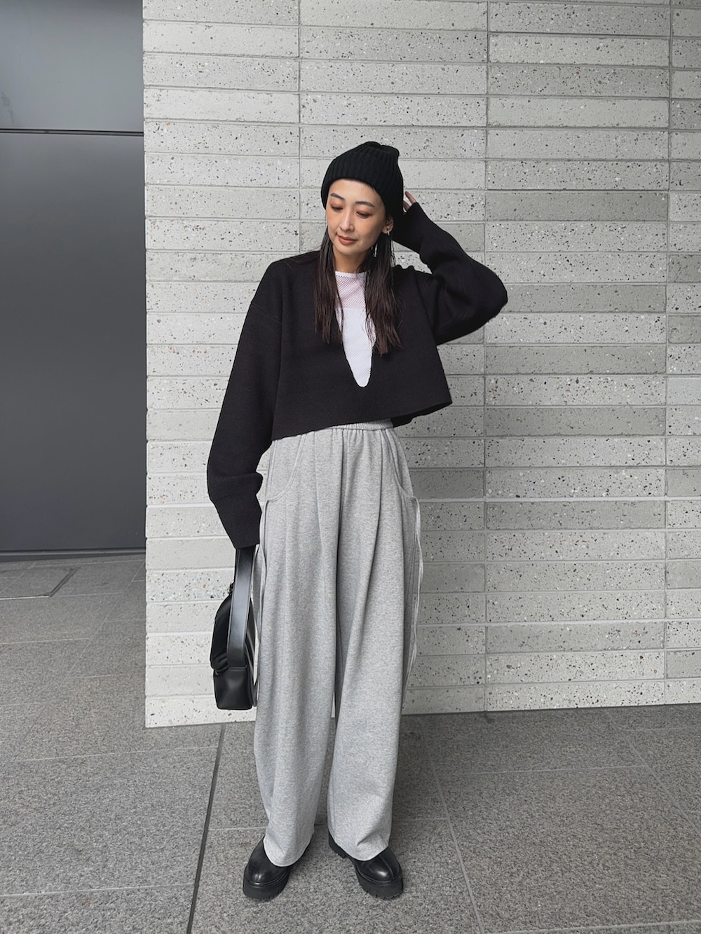 ブラック系のニット/セーター、グレー系のスウェットパンツ、ブラック系のショルダーバッグを着用したレディースの秋コーディネートの4枚目の写真