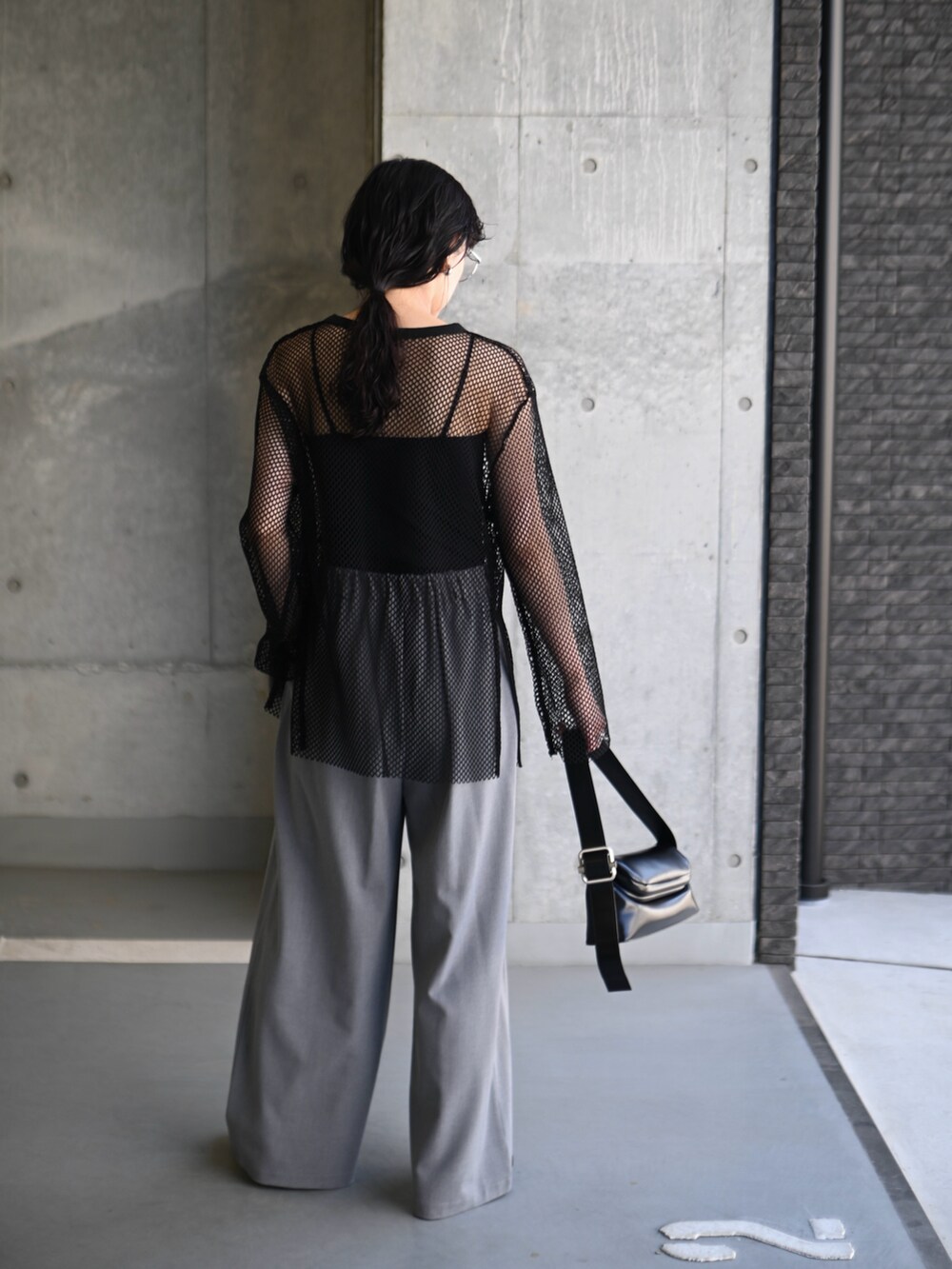 ブラック系のTシャツ/カットソー、ブラック系のショルダーバッグ、グレー系のスラックスを着用したレディースの夏コーディネートの4枚目の写真