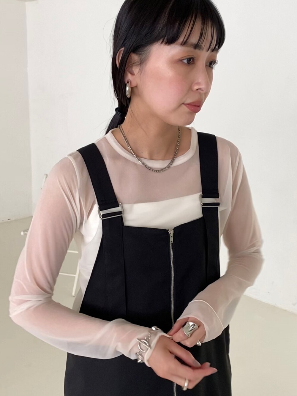 ブラック系のジャンパースカート、ホワイト系のTシャツ/カットソー、ホワイト系のキャミソールを着用したレディースの夏コーディネートの3枚目の写真