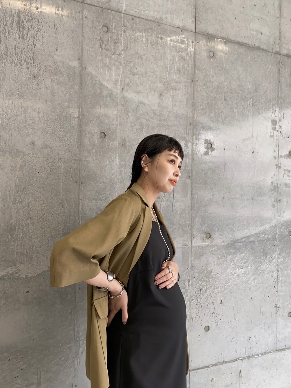 グリーン系のテーラードジャケット、ブラック系のワンピース、ブラック系のサンダルを着用したレディースの夏コーディネートの4枚目の写真