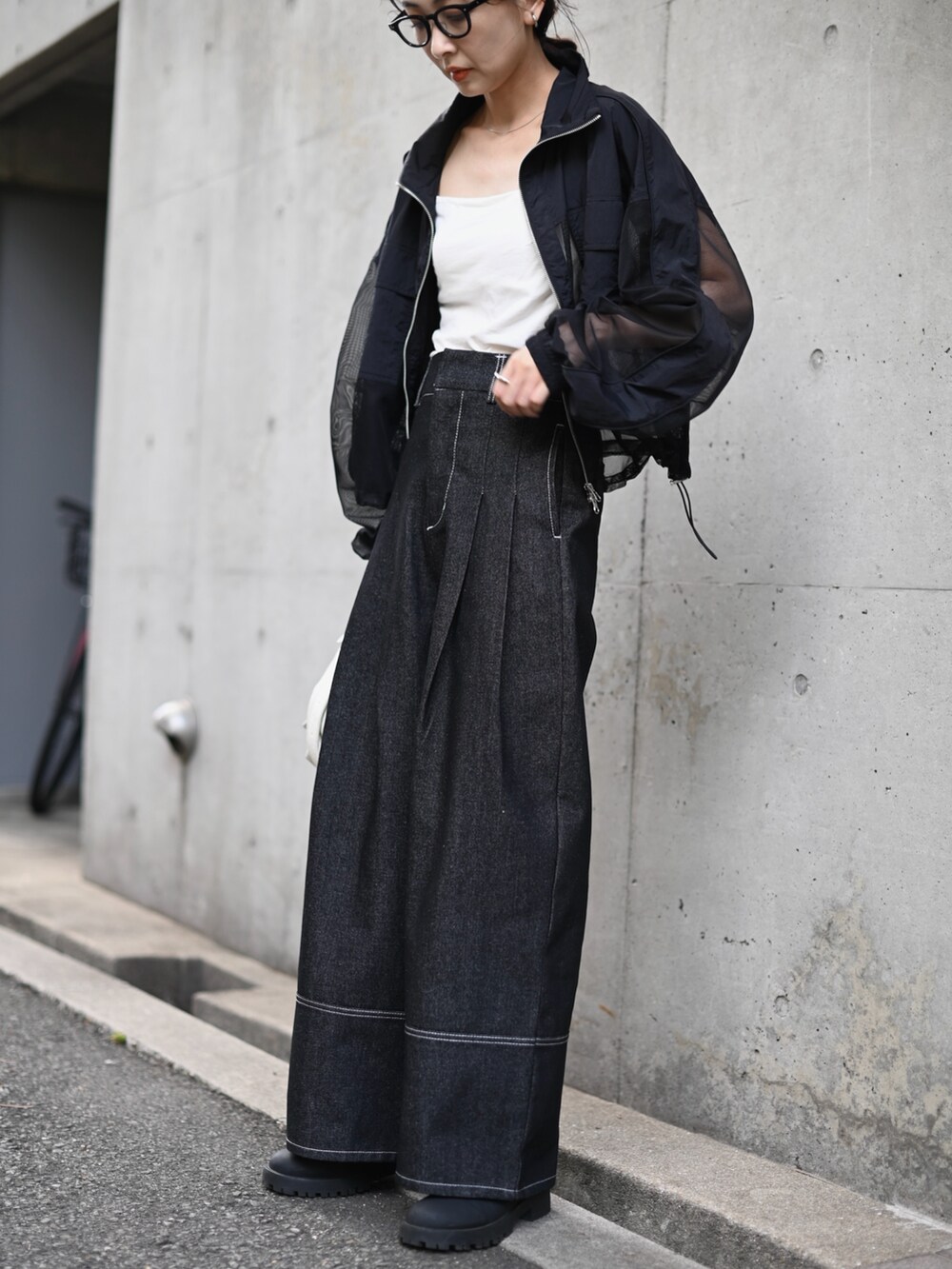 ブラック系のブルゾン、ブラック系のデニムパンツ、ホワイト系のショルダーバッグを着用したレディースの秋コーディネートの4枚目の写真