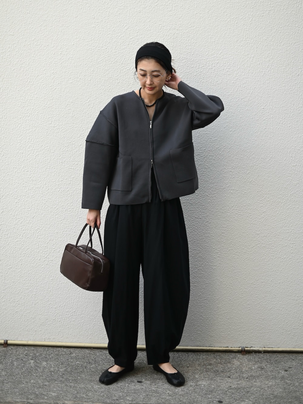 グレー系のカーディガン/ボレロ、ブラウン系のハンドバッグ、ブラック系のスラックスを着用したレディースの冬コーディネートの4枚目の写真