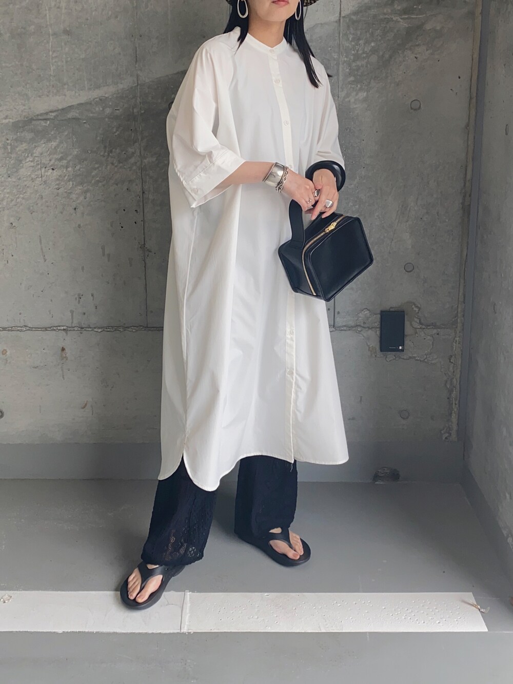 ホワイト系のシャツワンピース、ブラック系のその他パンツ、ブラック系のサンダルを着用したレディースの夏コーディネートの2枚目の写真