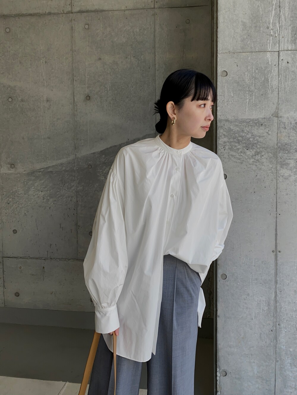 ホワイト系のシャツ/ブラウス、グレー系のスラックス、ブラウン系のショルダーバッグを着用したレディースの春コーディネートの3枚目の写真