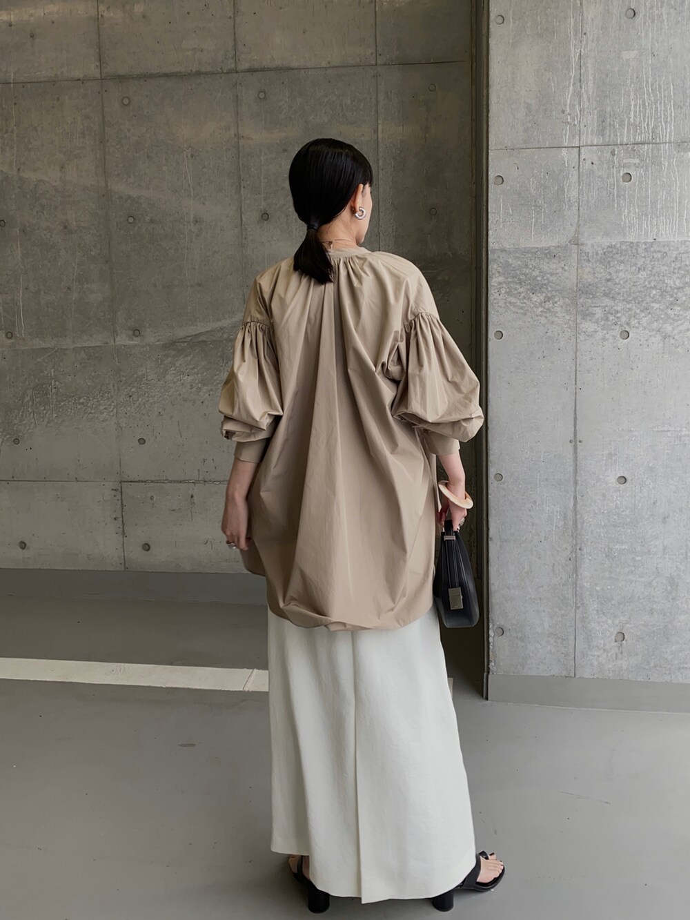 ベージュ系のシャツ/ブラウス、ホワイト系のスカート、ブラック系のハンドバッグを着用したレディースの春コーディネートの2枚目の写真