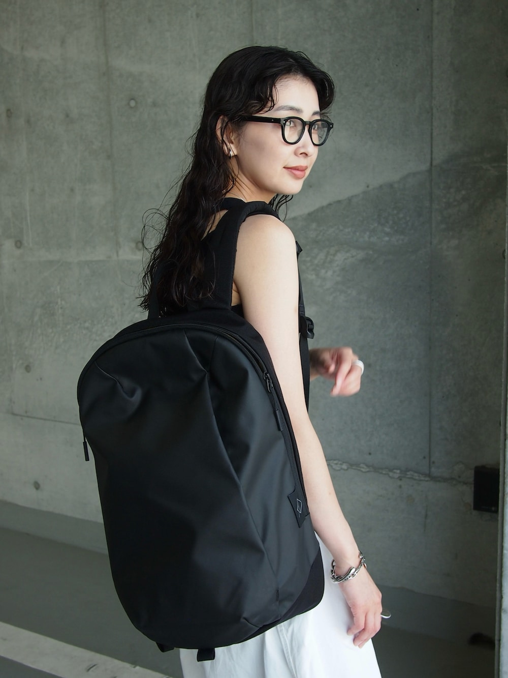 ブラック系のバックパック/リュック、ブラック系のスニーカー、ブラック系のタンクトップを着用したレディースの夏コーディネートの4枚目の写真