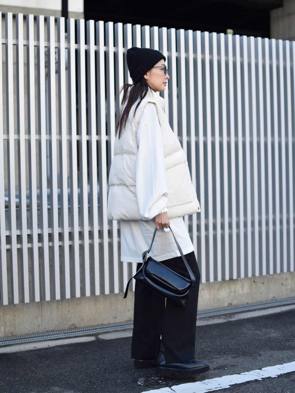 ホワイト系のダウンベスト、ブラック系のその他パンツ、ブラック系のショルダーバッグを着用したレディースの冬コーディネートの4枚目の写真