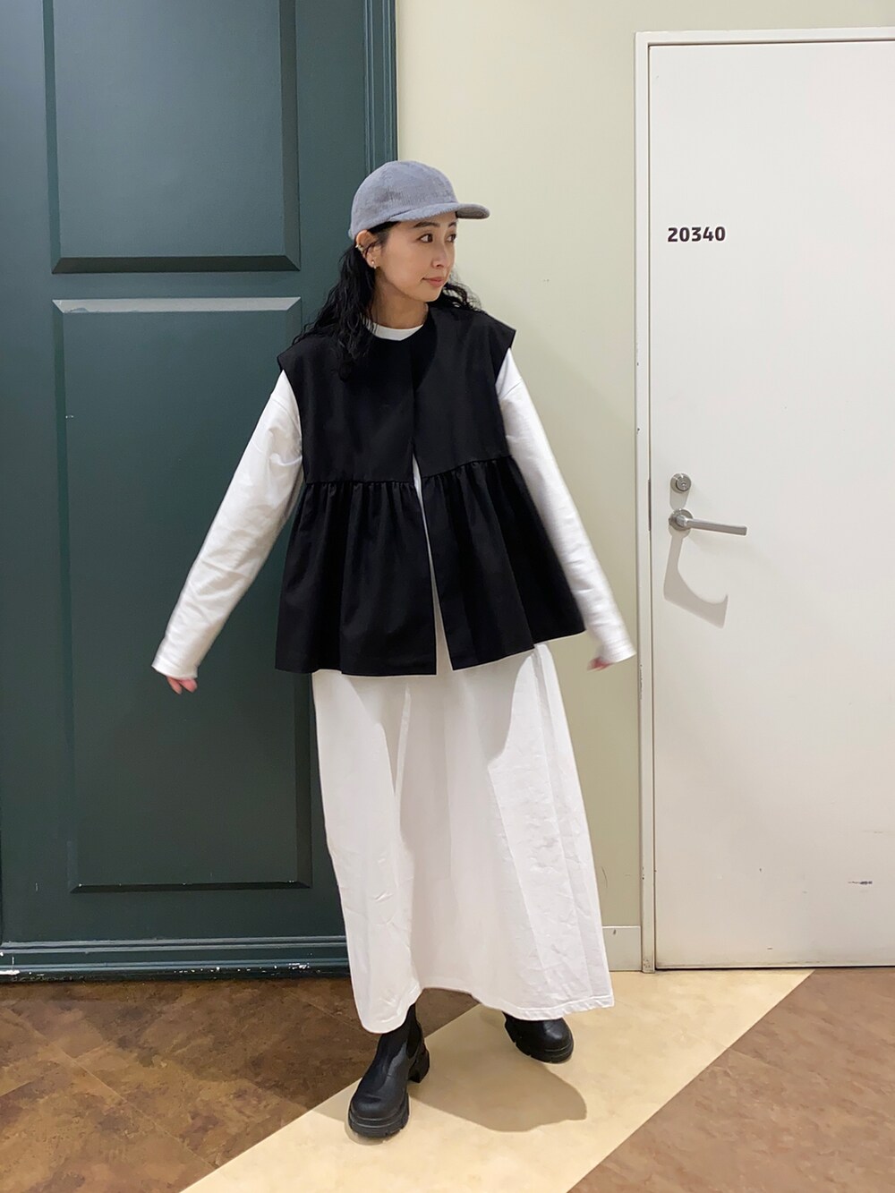 ブラック系のその他アウター、ブラック系のブーツ、グレー系のキャップを着用したレディースの秋コーディネートの2枚目の写真