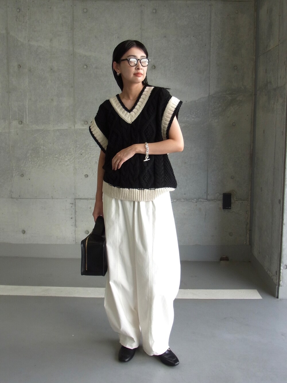 ブラック系のベスト、ホワイト系のチノパンツ、ブラック系のローファーを着用したレディースの夏コーディネートの3枚目の写真