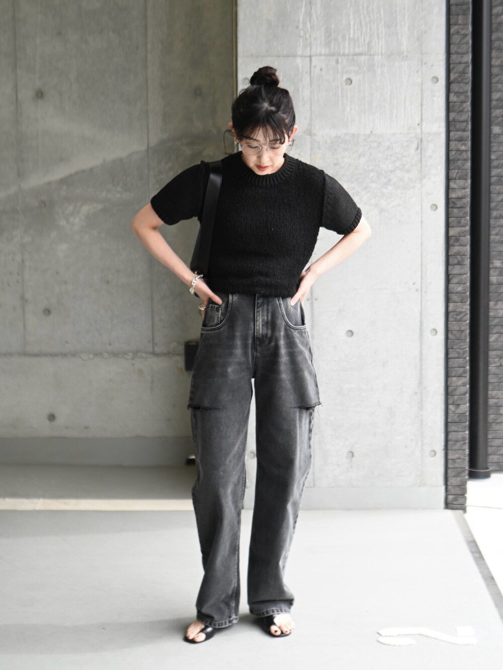 ブラック系のデニムパンツ、ブラック系のショルダーバッグ、ブラック系のニット/セーターを着用したレディースの春コーディネートの5枚目の写真