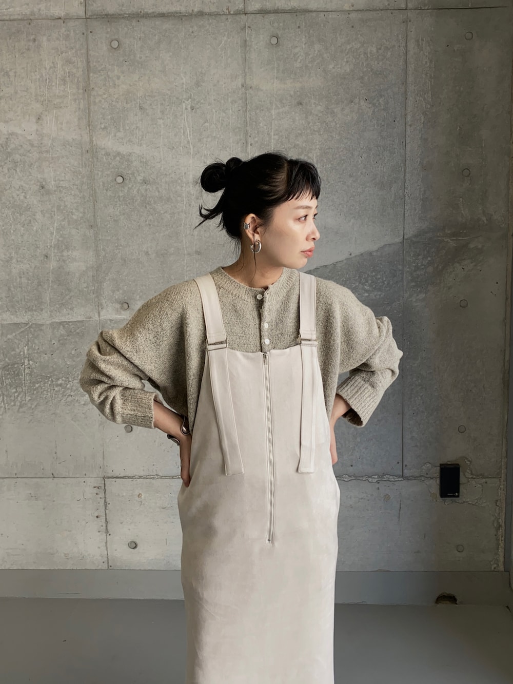 ホワイト系のジャンパースカート、グレー系のニット/セーター、ブラック系のブーツを着用したレディースの秋コーディネートの2枚目の写真