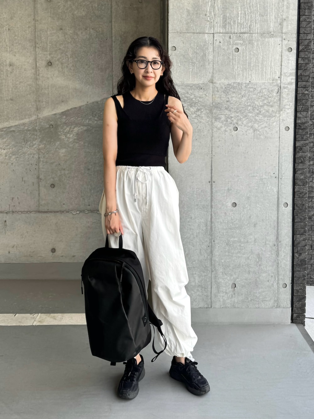 ブラック系のバックパック/リュック、ブラック系のスニーカー、ブラック系のタンクトップを着用したレディースの夏コーディネートの2枚目の写真