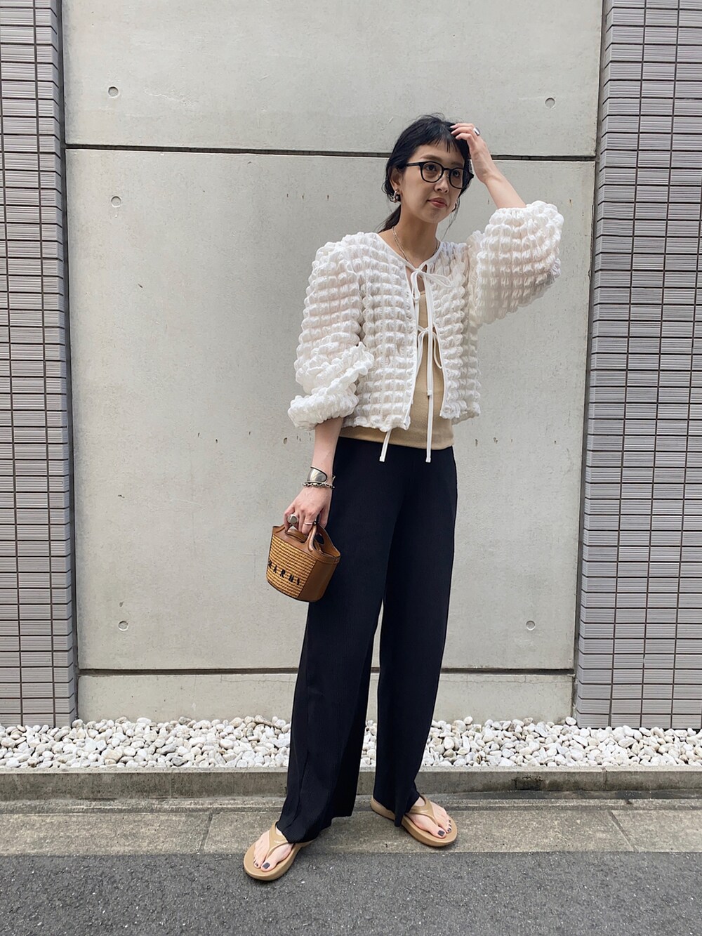 ホワイト系のトップス、ベージュ系のショルダーバッグ、ベージュ系のサンダルを着用したレディースの夏コーディネートの3枚目の写真