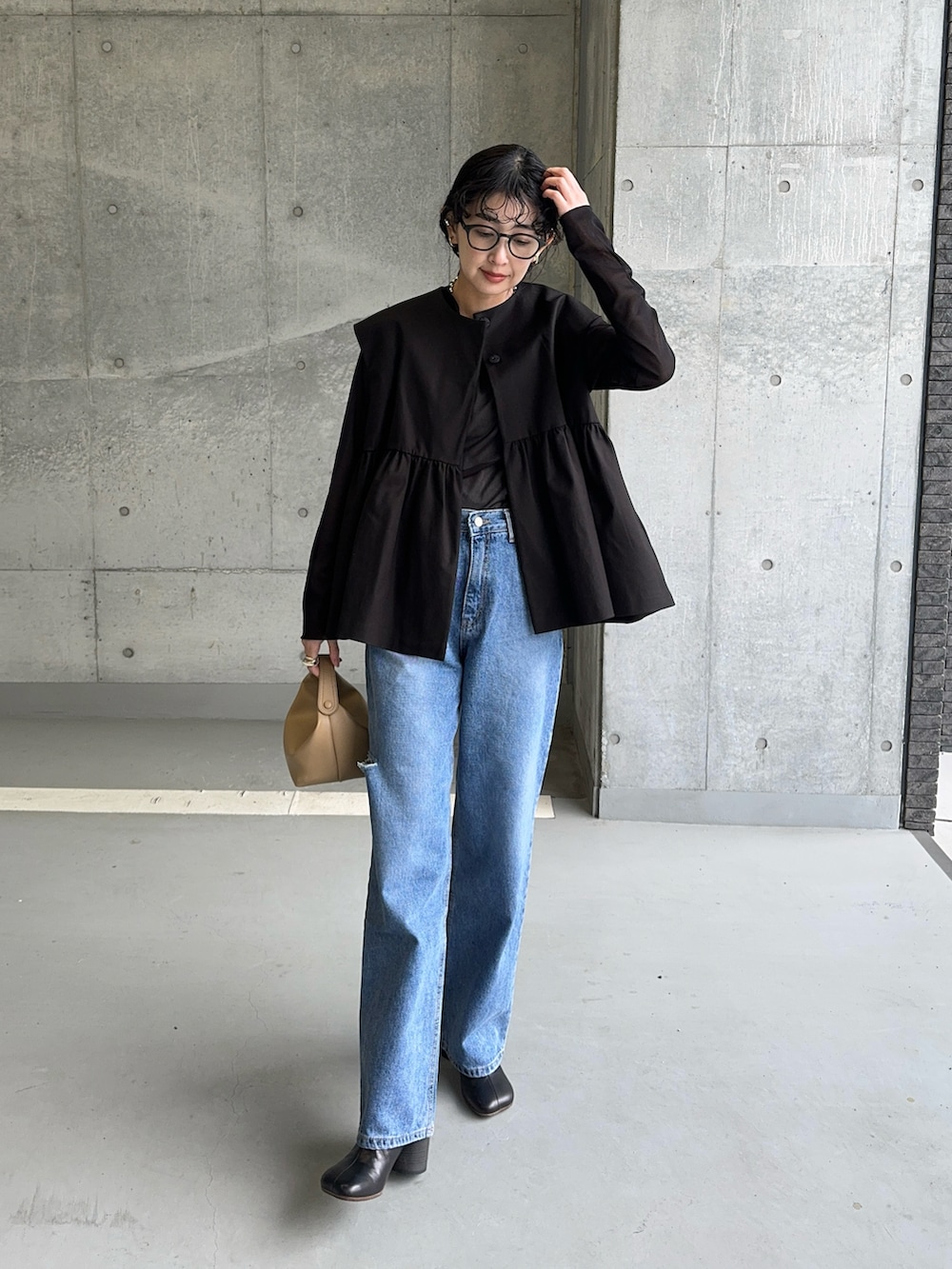 ブラック系のベスト、ブラック系のTシャツ/カットソー、ブルー系のデニムパンツを着用したレディースの春コーディネートの5枚目の写真