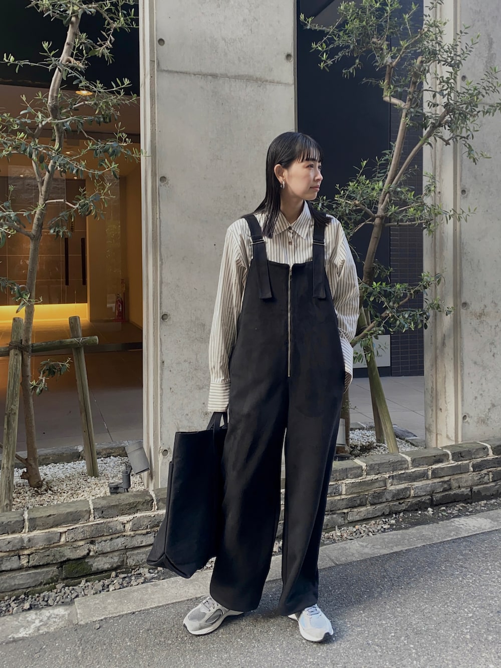 ブラック系のサロペット/オーバーオール、グレー系のスニーカー、ブラック系のトートバッグを着用したレディースの冬コーディネートの2枚目の写真