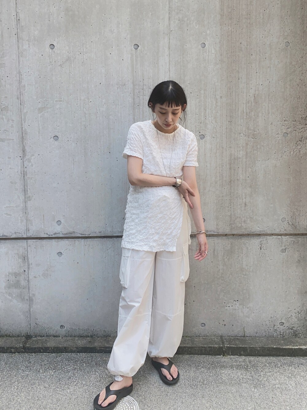 ホワイト系のTシャツ/カットソー、ホワイト系のパンツ、ブラック系のサンダルを着用したレディースの夏コーディネートの2枚目の写真