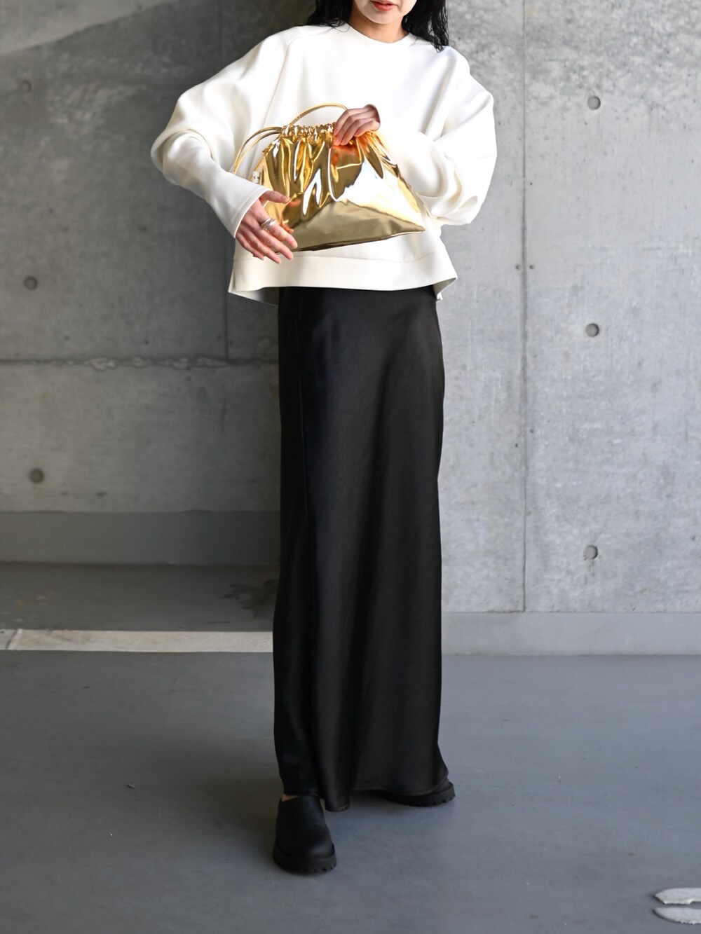 ホワイト系のスウェット、ブラック系のスカート、ゴールド系のショルダーバッグを着用したレディースの春コーディネートの3枚目の写真