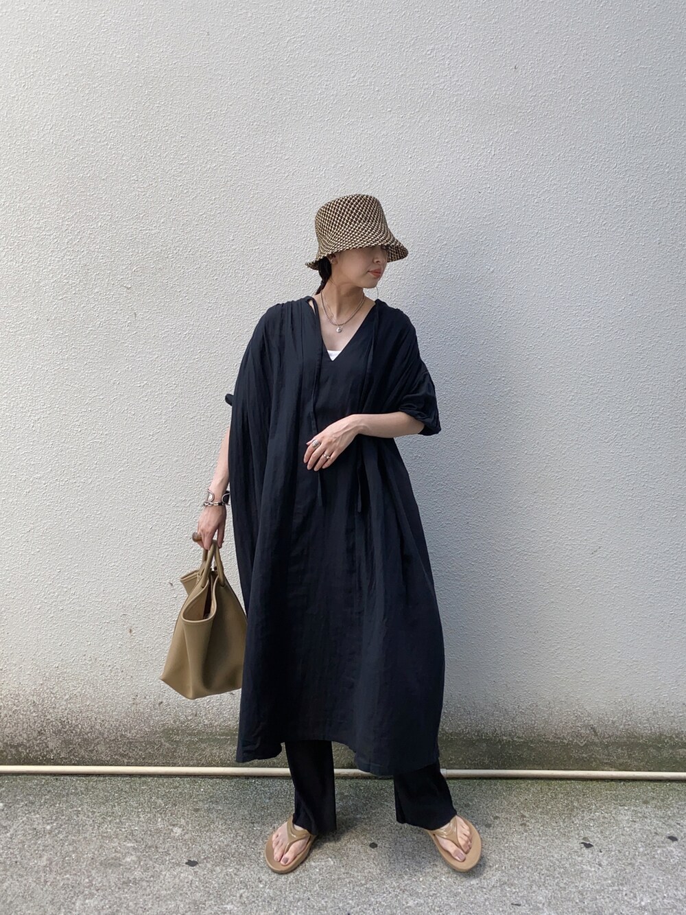 ブラック系のワンピース、ベージュ系のハンドバッグ、ベージュ系のサンダルを着用したレディースの夏コーディネートの4枚目の写真