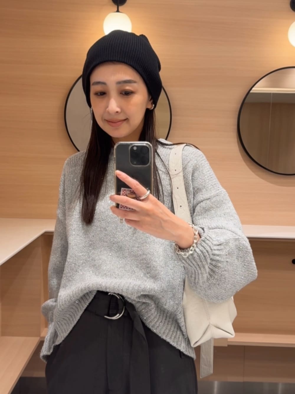 グレー系のニット/セーター、ホワイト系のショルダーバッグ、グレー系のパンツを着用したレディースの秋コーディネートの5枚目の写真