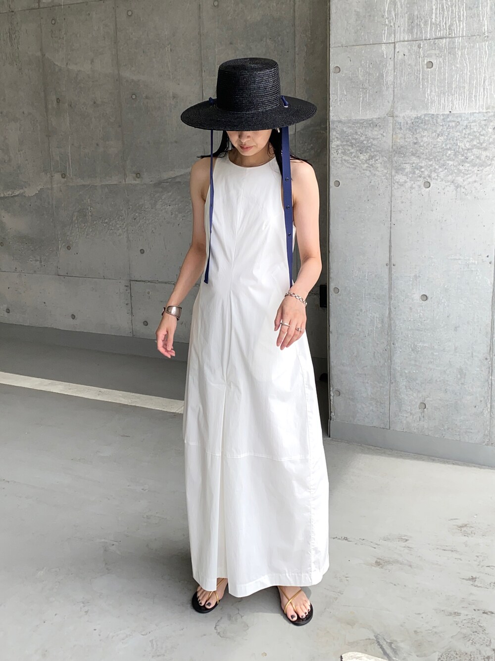 ホワイト系のワンピース、ゴールド系のサンダル、ブラック系のハットを着用したレディースの夏コーディネートの3枚目の写真