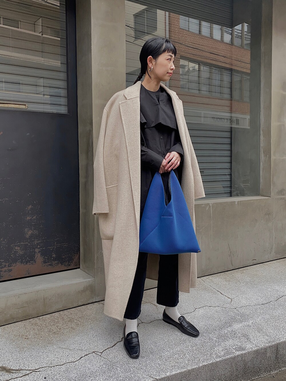 ブラック系のシャツ/ブラウス、ブルー系のハンドバッグ、ホワイト系のチェスターコートを着用したレディースの冬コーディネートの4枚目の写真