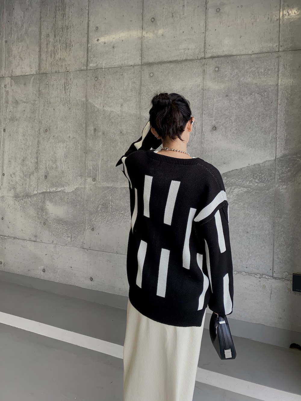 ブラック系のカーディガン/ボレロ、ホワイト系のスカート、ブラック系のハンドバッグを着用したレディースの冬コーディネートの2枚目の写真