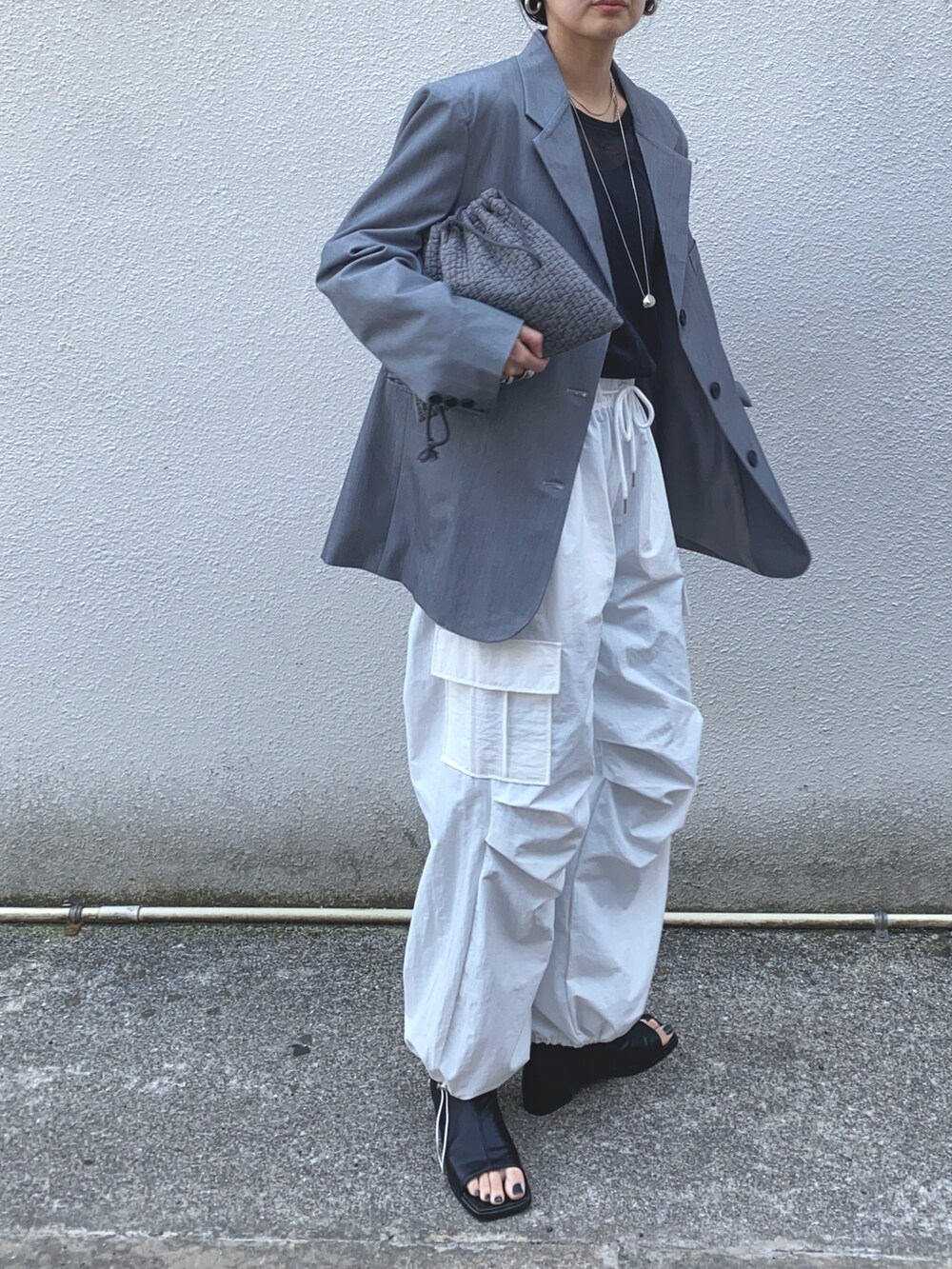 グレー系のテーラードジャケット、ホワイト系のカーゴパンツ、シルバー系のネックレスを着用したレディースの春コーディネートの2枚目の写真