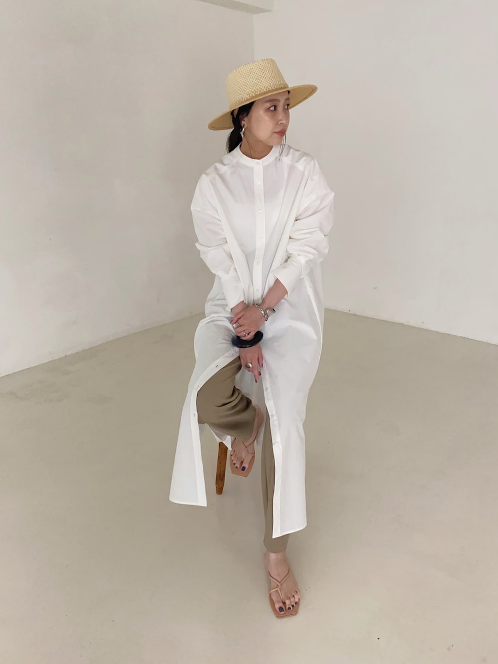 ベージュ系のパンツ、ホワイト系のシャツワンピース、ブラック系のブレスレットを着用したレディースの夏コーディネートの2枚目の写真