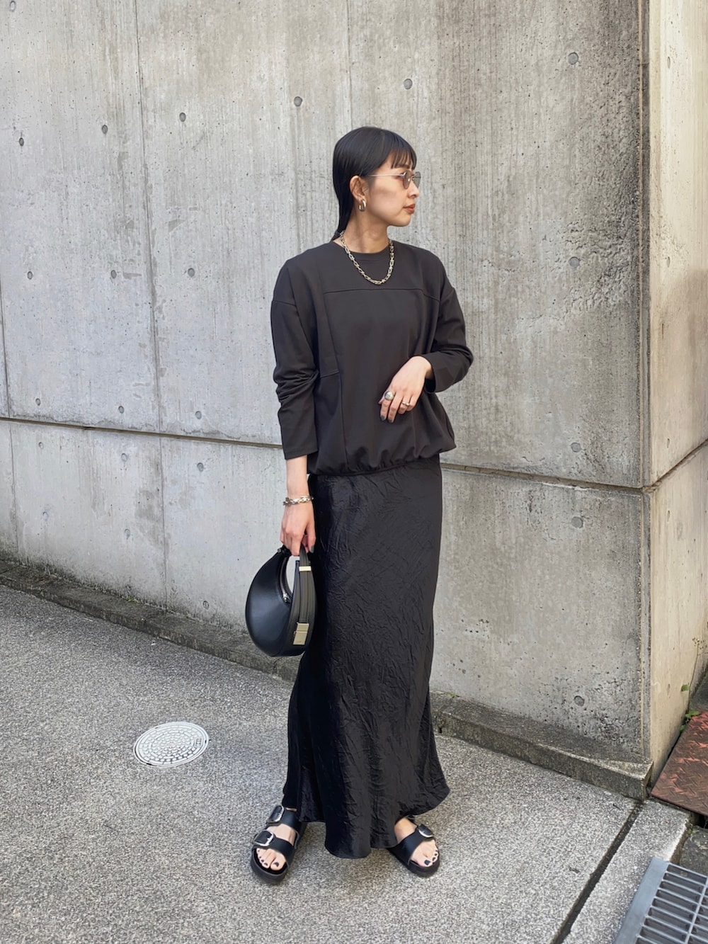 ブラック系のスカート、ブラック系のハンドバッグ、ブラック系のサンダルを着用したレディースの春コーディネートの2枚目の写真