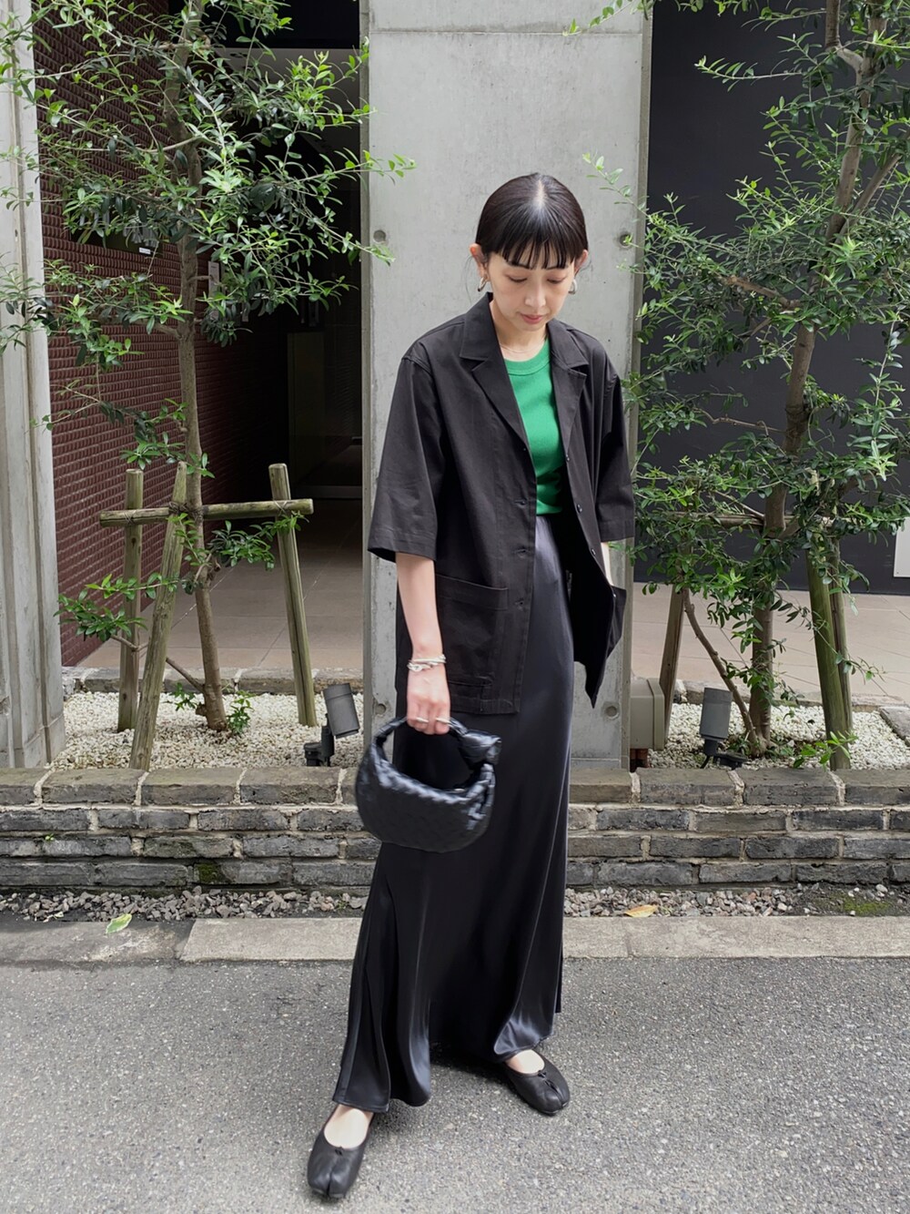 ブラック系のその他アウター、ブラック系のスカート、ブラック系のハンドバッグを着用したレディースの秋コーディネートの3枚目の写真