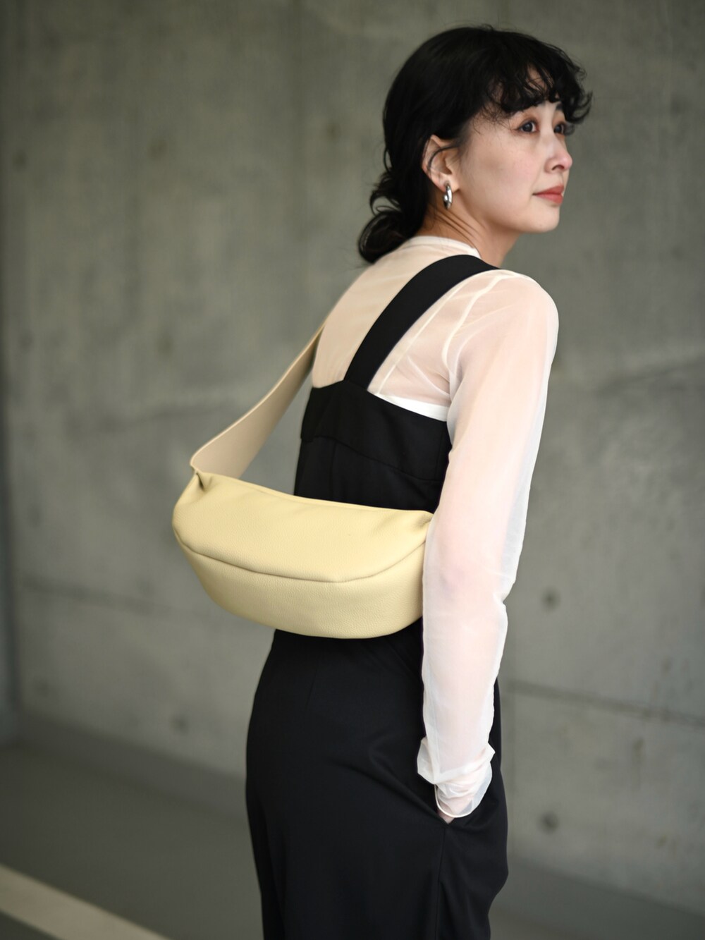 ブラック系のサロペット/オーバーオール、ホワイト系のキャミソール、ベージュ系のショルダーバッグを着用したレディースの春コーディネートの3枚目の写真