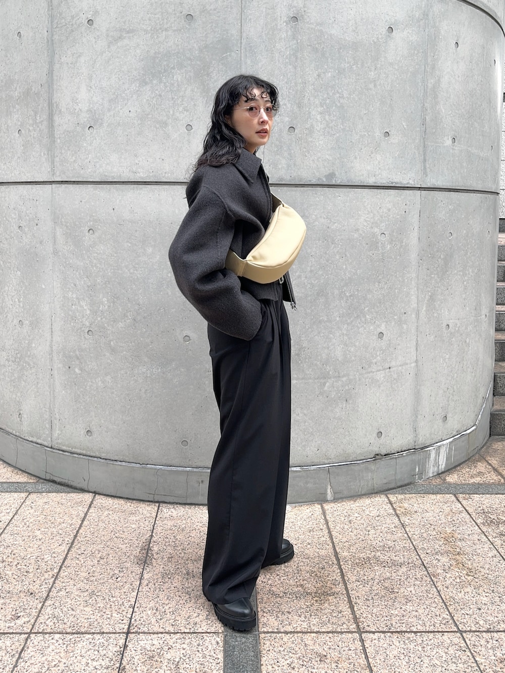 グレー系のブルゾン、ブラック系のスラックス、ブラック系のブーツを着用したレディースの冬コーディネートの4枚目の写真